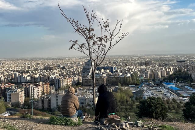 Varias personas contemplan la ciudad desde el parque Pardisan, en Teherán (Irán), el 14 de abril de 2026. (AFP vía Getty Images)