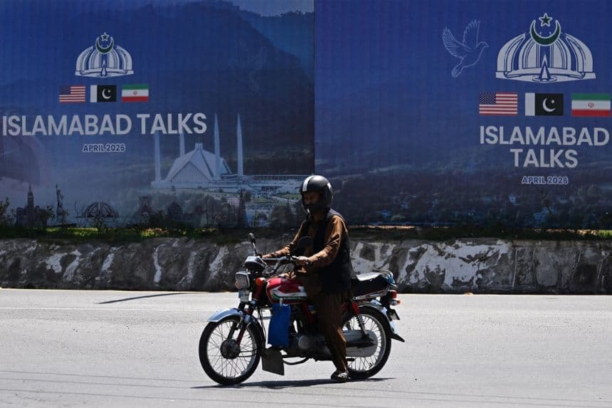 Un viajero pasa junto a una valla publicitaria de las conversaciones de paz entre Estados Unidos e Irán en Islamabad, el 13 de abril de 2026. (Aamir Qureshi/AFP vía Getty Images)