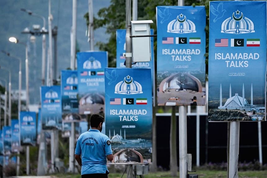 Un agente de policía pasa junto a unos carteles que destacan la mediación de Pakistán en las conversaciones de paz entre Irán y Estados Unidos, en la zona conocida como la Zona Roja de Islamabad, el 18 de abril de 2026.(Farooq NAEEM / AFP vía Getty Images)