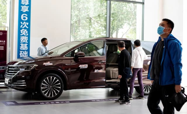 Varias personas observan un carro Volkswagen expuesto en un concesionario de Beijing el 10 de mayo de 2020. (Noel Celis/AFP vía Getty Images)