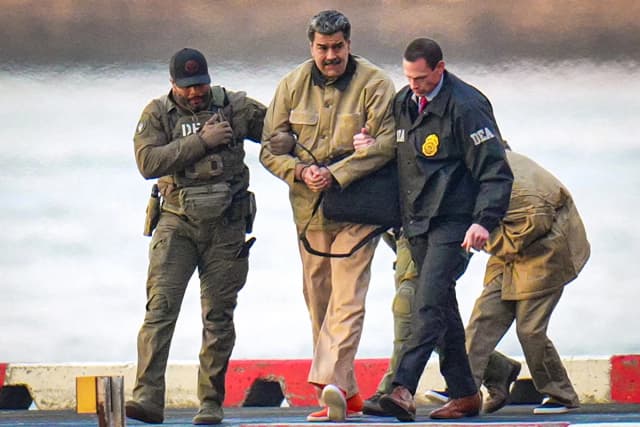 Nicolás Maduro y su esposa, Cilia Flores (al fondo), son escoltados por agentes federales tras aterrizar en un helipuerto de Manhattan, mientras se dirigen a un vehículo blindado para dirigirse a un tribunal federal de la ciudad de Nueva York el 5 de enero de 2026. (XNY/Star Max/GC Images)