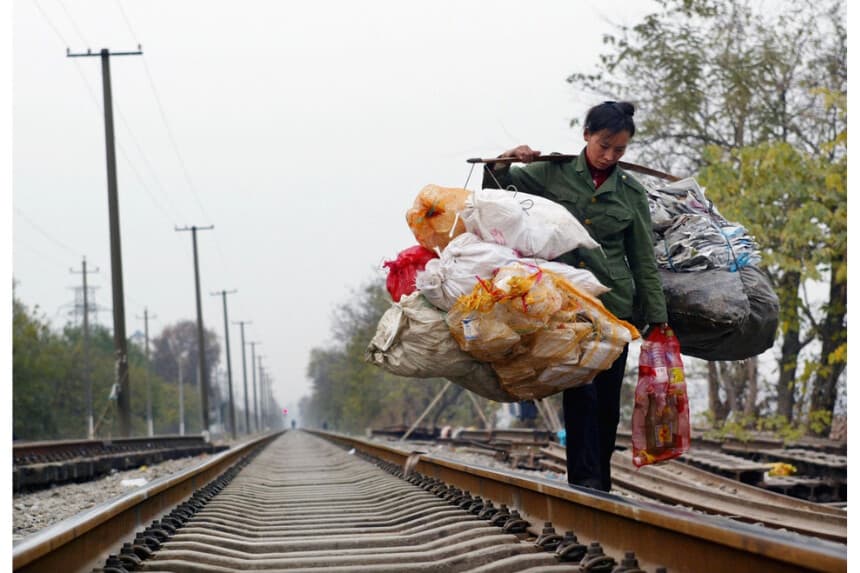 Trabajadora migrante chino que transportaba basura camina en un ferrocarril en Wuhan, provincia de Hubei, China, el 6 de diciembre de 2004. (Fotos de China/GettyImages)