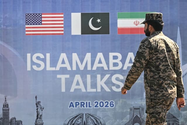 Un ranger pakistaní pasa junto a una valla publicitaria de las conversaciones de paz entre Estados Unidos e Irán, en Islamabad, el 12 de abril de 2026. (Farooq Naeem/AFP vía Getty Images)