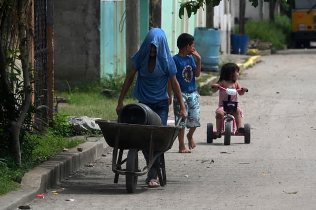 Aquí tienes la traducción:
Niños son vistos en una calle de Chamelecón, en las afueras de San Pedro Sula, Honduras, el 16 de julio de 2022. Chamelecón está bajo el control de pandillas, con una calle que divide los dominios de las bandas Barrio 18 y Mara Salvatrucha (MS-13).(ORLANDO SIERRA/AFP via Getty Images)