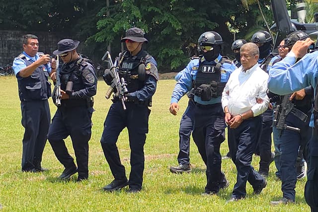 El exalcalde de Tocoa Adán Fúnez (d), implicado en el asesinato del ambientalista Juan López, el 14 de septiembre de 2024, es escoltado en una base policial tras su captura este martes, en La Ceiba, Honduras. (EFE/Cesar Fúnez)