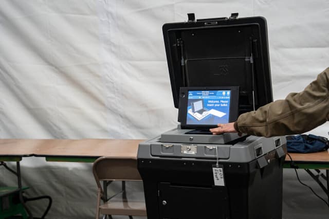 Foto Ilustrativa: Un funcionario electoral toca una máquina de votación dentro de una carpa el día de las elecciones, el 5 de noviembre de 2024 en Burnsville, Carolina del Norte. (Foto de Allison Joyce / AFP) (ALLISON JOYCE/AFP vía Getty Images).
