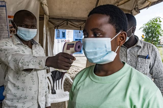 Una autoridad de salud en el paso fronterizo de Busunga, entre Uganda y la República Democrática del Congo, toma la temperatura a un viajero en Bundibugyo el 18 de mayo de 2026. (Badru Katumba/AFP vía Getty Images).