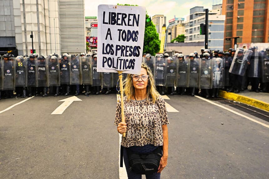 Una mujer sostiene un cartel en el que se lee "Liberen a todos los presos políticos" durante una protesta tras la muerte de Carmen Navas, madre del fallecido preso político Víctor Quero Navas, en Caracas, el 18 de mayo de 2026. (Juan BARRETO / AFP vía Getty Images)