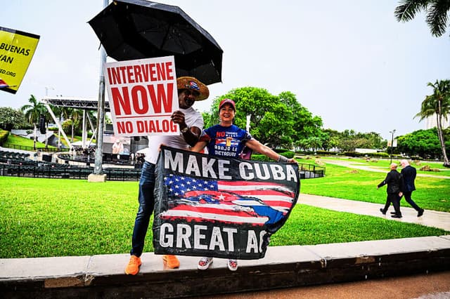 La gente sostiene pancartas y carteles bajo la lluvia durante una manifestación por una «Cuba libre» en Miami, Florida, el 26 de abril de 2026, para pedir la salida de los Castro y del Partido Comunista del poder en Cuba. (CHANDAN KHANNA / AFP vía Getty Images)
