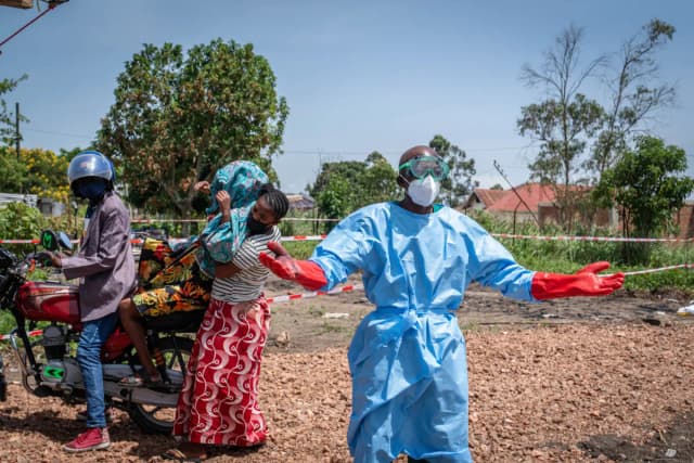 Dieudonné Sezabo (derecha), un trabajador sanitario, gesticula mientras pide ayuda para transportar a un paciente (segundo por la izquierda) con sospecha de ébola, que fue trasladado en mototaxi al hospital de Rwampara en Ituri, Congo, el 26 de mayo de 2026. (Glody Murhabazi/AFP vía Getty Images).