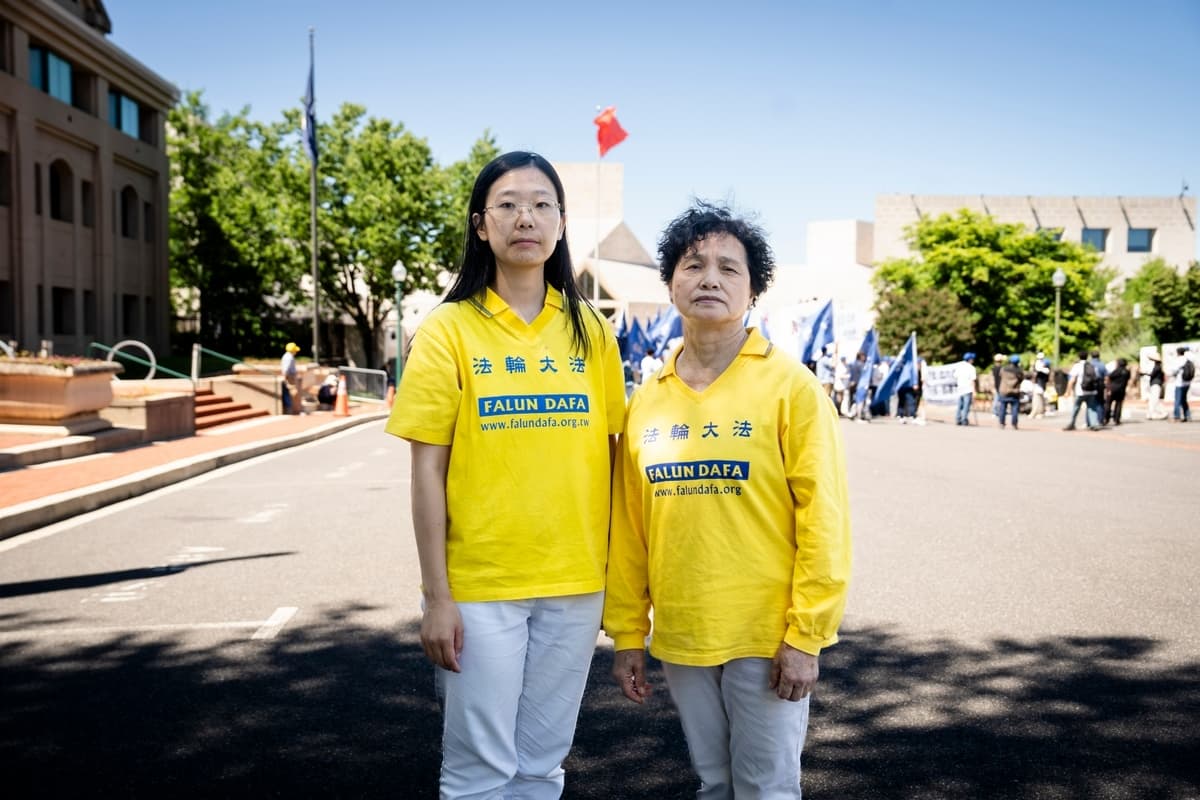 Las practicantes de Falun Gong Alisa Zhou (izquierda) y Tong Shuzhen posan frente a la embajada china en Washington el 30 de mayo de 2026. (Madalina Kilroy/The Epoch Times)
