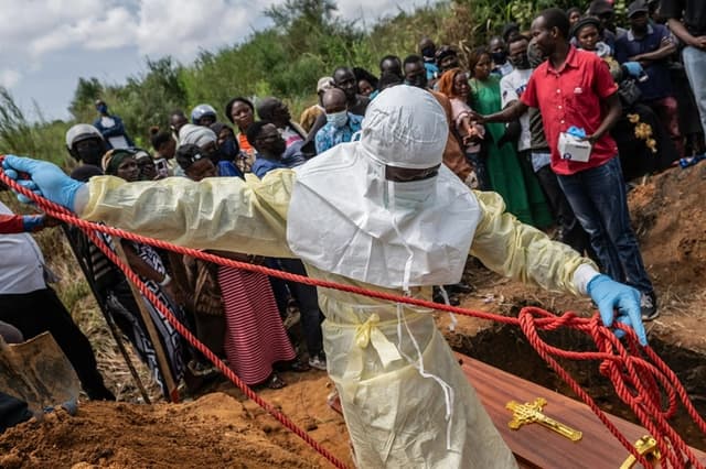 Trabajadores de la Cruz Roja preparan un ataúd con el cadáver de una víctima del ébola para su entierro en el cementerio de Rwampara, en Rwampara (Congo), el 23 de mayo de 2026. (Moses Sawasawa/AP Photo)
