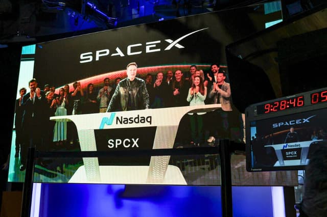 El director ejecutivo de SpaceX, Elon Musk, que aparece en una pantalla conectada a distancia desde la sede de SpaceX en Starbase, Texas, pronuncia unas palabras antes del lanzamiento de la oferta pública inicial (OPI) de SpaceX en el Nasdaq MarketSite de Nueva York, el 12 de junio de 2026. Timothy A. (Clary / AFP vía Getty Images).