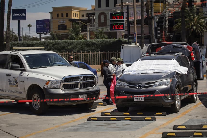 Integrantes de la Policía de México custodian la zona de un crimen este sábado, en Tijuana (México). El hallazgo de un cadáver humano en avanzado estado de descomposición dentro de un vehículo estacionado en las inmediaciones del estadio donde entrena la selección de Irán para el Mundial 2026 volvió a colocar a la ciudad mexicana de Tijuana en el foco de la atención internacional, en medio de la presencia de equipos y aficionados de distintos países. (EFE/Joebeth Terríquez)