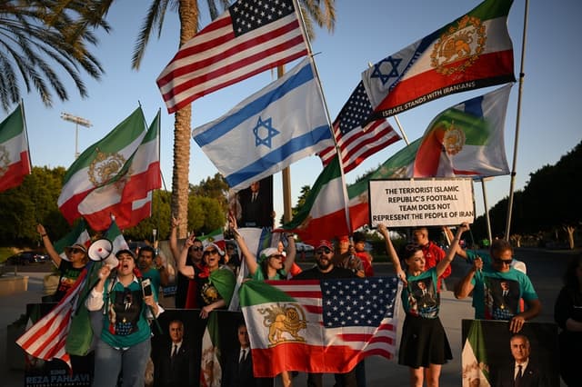 La gente sostiene banderas iraníes prerrevolucionarias mientras protesta contra el régimen iraní frente al Carson Sports Park antes de la sesión de entrenamiento de Irán en Los Ángeles el 14 de junio de 2026, en vísperas del partido de fútbol de la Copa del Mundo de 2026 entre Irán y Nueva Zelanda. (Patrick T. Fallon / AFP vía Getty Images)