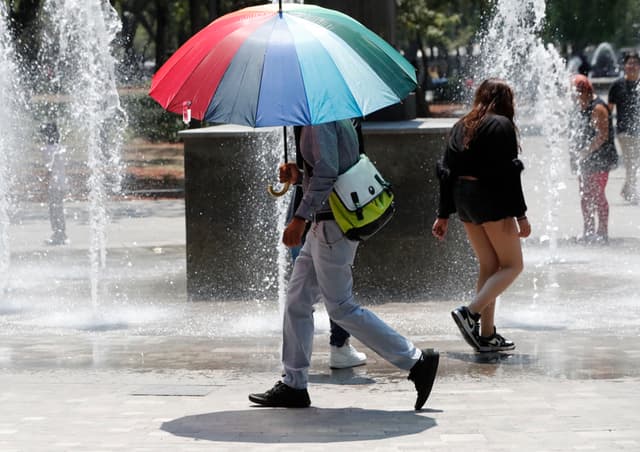 Una persona utiliza una sombrilla para protegerse del sol durante un día caluroso, en Ciudad de México. Imagen de archivo. (EFE/ Mario Guzmán)