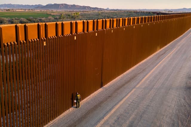 Panorámica aérea de un agente de la Patrulla Fronteriza de EE. UU. que busca huellas de migrantes junto a la valla en Yuma, Arizona, el 9 de marzo de 2024. La frontera entre Estados Unidos y México. (John Moore/Getty Images).