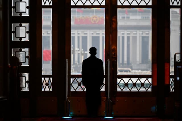 Un guardia de seguridad permanece en su puesto durante la sesión inaugural de la Asamblea Popular Nacional (APN) en el Gran Salón del Pueblo de Beijing, el 5 de marzo de 2024. (Wang Zhao/AFP vía Getty Images).