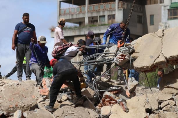 Varias personas y equipos de rescate trabajan entre los escombros de un edificio derrumbado tras los terremotos de magnitud 7.2 y 7.5 que sacudieron Venezuela y otras regiones del Caribe el 25 de junio de 2026 en Caracas, Venezuela. (Edilzon Gamez/Getty Images)