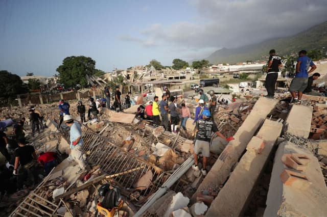 Imagen de personas realizando labores de búsqueda en una zona afectada por un terremoto, el viernes en La Guaira, Venezuela. (EFE/ Ronald Peña R)