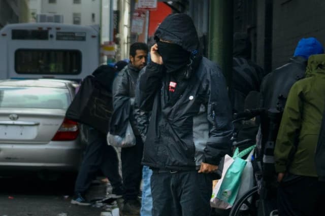 Un presunto narcotraficante se encuentra cerca de un grupo de drogadictos en San Francisco, California, el 23 de febrero de 2023. (John Fredricks/The Epoch Times)