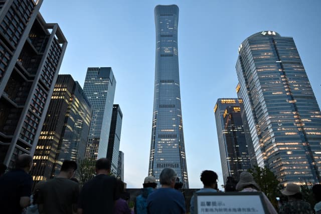 La gente se reúne cerca de la Torre CITIC en Beijing, después de que un testigo ocular informara de la presencia de restos de un avión en la base del edificio más alto de la ciudad, el 26 de junio de 2026. (Adek Berry/AFP vía Getty Images)