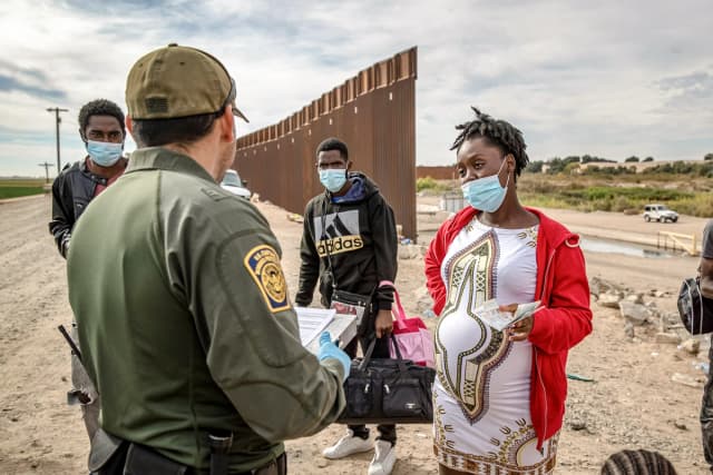 Un agente de la Patrulla Fronteriza de EE. UU. detiene a unos migrantes, entre ellos una mujer haitiana embarazada que busca dar a luz en Estados Unidos, en Yuma, Arizona, el 7 de diciembre de 2021. (John Moore/Getty Images)