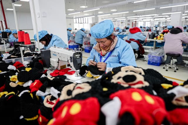 Empleados trabajan en una línea de producción de muñecas en una fábrica de juguetes en Lianyungang, en el este de la provincia de Jiangsu, China, el 13 de marzo de 2024. (STR/AFP vía Getty Images)