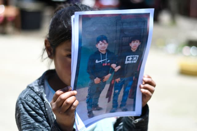 Una niña sostiene un retrato de Melvin Guachiac (izq.) y Wilmer Tulul —muertos dentro de un tráiler en Texas después de cruzar desde México— en la aldea de Tzucubal, Nahualá, Guatemala, el 30 de junio de 2022. (JOHAN ORDONEZ/AFP via Getty Images)