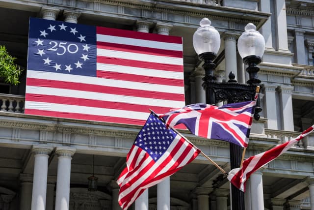 Las banderas de EE. UU. y del Reino Unido ondean junto a una bandera que celebra el 250.º aniversario de la independencia de Estados Unidos, antes de la visita de Estado del rey Carlos III y la reina Camilla de Gran Bretaña en Washington, el 27 de abril de 2026. (Ken Cedeno/AFP vía Getty Images)
