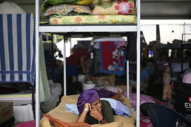 Un desplazado yace en una litera dentro de un refugio temporal instalado en el complejo deportivo José María Vargas, que acoge a personas desplazadas por los dos terremotos, en el estado de La Guaira (Venezuela), el 13 de julio de 2026. (Federico PARRA / AFP vía Getty Images)