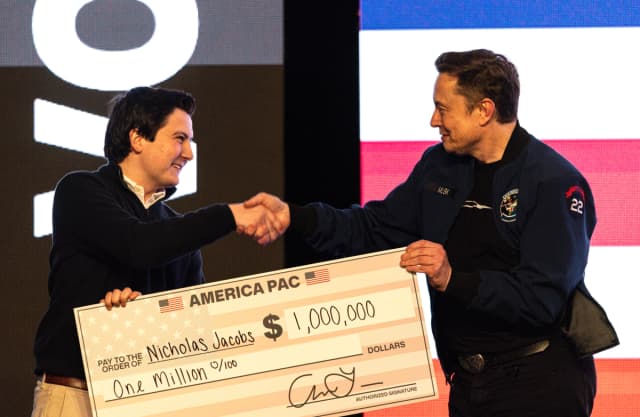 Elon Musk entrega un cheque de un millón de dólares a Nicholas Jacobs durante un encuentro público en Green Bay, Wisconsin, el 30 de marzo de 2025. (Jeffrey Phelps/AP Photo)