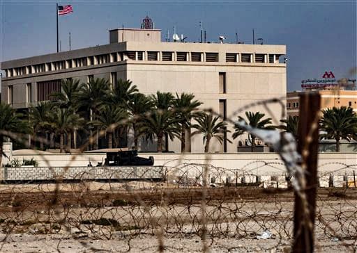 Un vehículo blindado y personal de la Embajada de Estados Unidos, pertenecientes a la embajada bareiní, refuerzan la seguridad en las inmediaciones de una puerta de acceso al edificio, rodeado de alambre de púas, en Manama, Baréin, el domingo 4 de agosto de 2013. (Foto AP/Hasan Jamali).