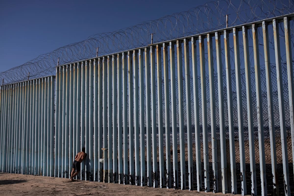 Un migrante hondureño mira a través del muro fronterizo en la playa de Tijuana, México, el 3 de diciembre de 2018. (Alkis Konstantinidis/Reuters).