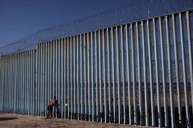 Un migrante hondureño mira a través del muro fronterizo en la playa de Tijuana, México, el 3 de diciembre de 2018. (Alkis Konstantinidis/Reuters).