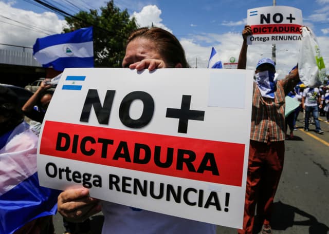 Una manifestante antigubernamental sostiene una pancarta con el lema «No más dictadura» mientras participa en una marcha para exigir la liberación de presos políticos, en Managua, el 15 de agosto de 2018. (INTI OCON/AFP via Getty Images)