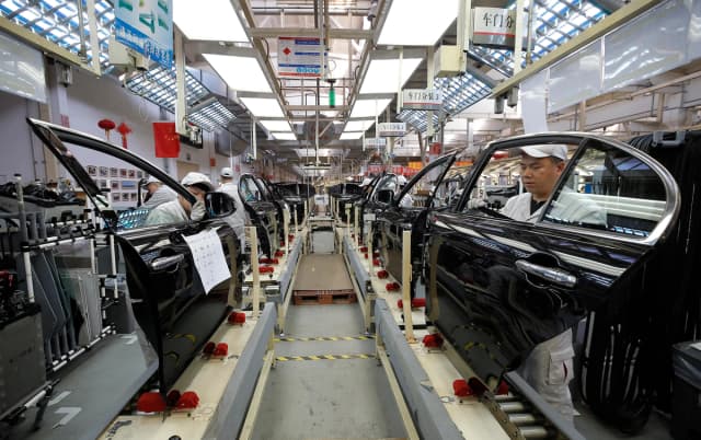 Empleados chinos trabajando en una línea de producción de automóviles en una fábrica en Changchun, en la provincia de Jilin, al noreste de China, el 1 de noviembre de 2017. (STR/AFP vía Getty Images)
