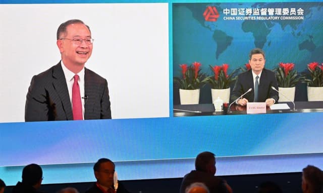 El director ejecutivo de la Autoridad Monetaria de Hong Kong (HKMA), Eddie Yue Wai-man (izquierda), habla con Fang Xinghai, vicepresidente de la Comisión Reguladora de Valores de China (derecha), a través de un enlace de video durante la inauguración de la Cumbre de Inversión de Líderes Financieros Globales en Hong Kong el 2 de noviembre de 2022. (Peter Parks/AFP)