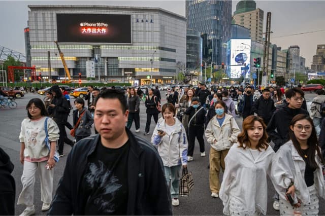 Varias personas cruzan la calle en un semáforo en Pekín el 8 de abril de 2025. (Kevin Frayer / Getty Images).