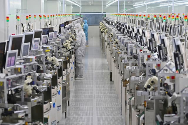Técnicos trabajan en equipos de procesamiento de chips en una planta de fabricación de semiconductores en Suqian, China, el 20 de octubre de 2025. (STR/AFP vía Getty Images).