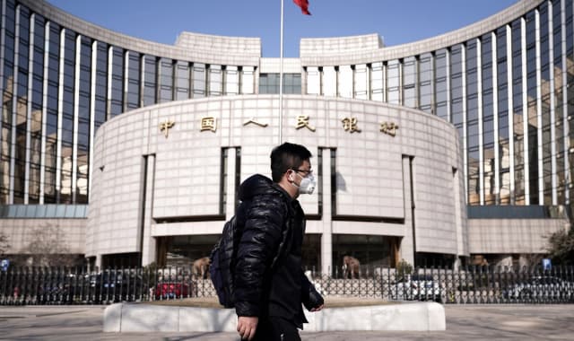Un hombre con cubrebocas pasa frente a la sede del Banco Popular de China, el banco central, en Beijing, China, el 3 de febrero de 2020. (Jason Lee/Reuters)
