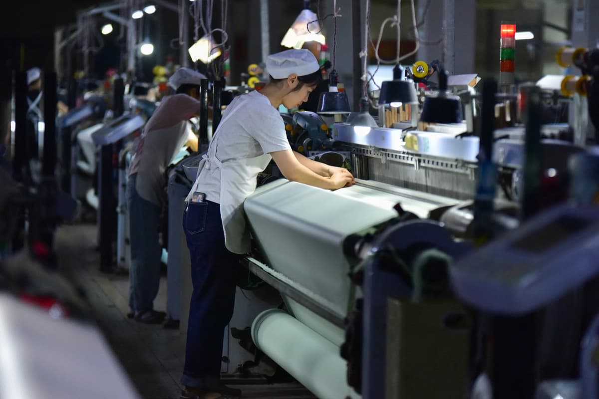 Empleados trabajan en la línea de producción de la empresa Anhui Jingjiu Silk Company en Fuyang, provincia de Anhui, al este de China, el 20 de octubre de 2025. (-STR/AFP vía Getty Images)