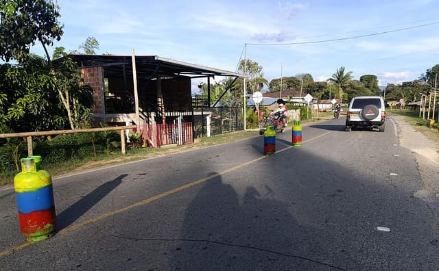 Vehículos pasan junto a cilindros que, según se afirma, fueron colocados por disidentes de las FARC en la carretera, en el departamento del Cauca, Colombia, el 14 de septiembre de 2025. (PEDRO MORALES/AFP vía Getty Images)