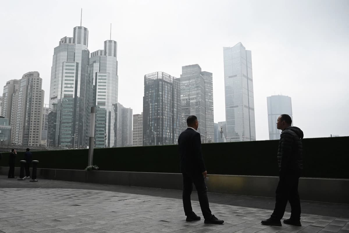 Dos hombres conversan frente a edificios de oficinas en el distrito financiero central de Beijing el 4 de marzo de 2026. (Greg Baker/AFP vía Getty Images).