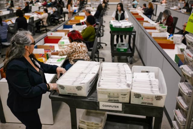 Un funcionario electoral traslada las papeletas de voto por correo para su posterior recuento en el Centro de Procesamiento de Votos del Condado de Los Ángeles durante las elecciones primarias estatales de California en City of Industry, California, el 2 de junio de 2026. (Patrick T. Fallon / AFP vía Getty Images)