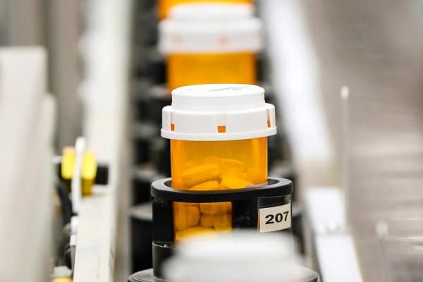 En esta foto de archivo, se ven frascos de medicamentos llenándose mientras avanzan por líneas automatizadas. (Foto de George Frey/Getty Images).