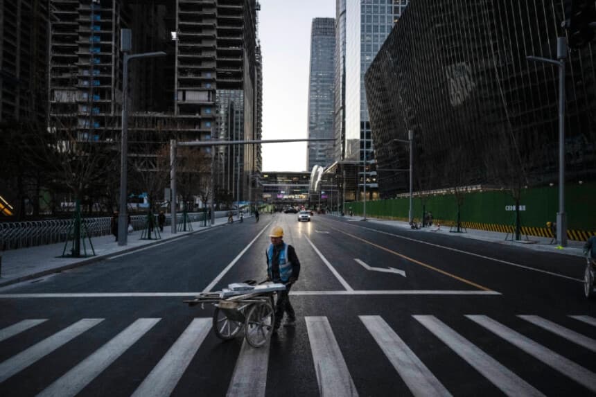 Un obrero de la construcción empuja una carretilla cargada de materiales por la calle en el distrito financiero central de Pekín, China, el 29 de noviembre de 2024. (Kevin Frayer/Getty Images).