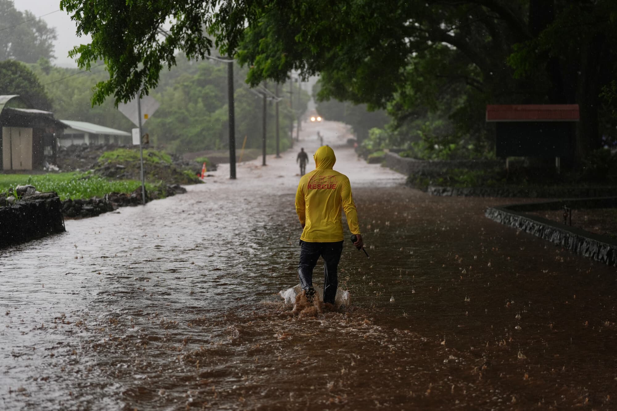 El capitán de bomberos Lui Sales, del Departamento de Bomberos de Hawái, busca residentes que puedan ayudar mientras el agua de lluvia del cercano huracán Nolo inunda un tramo de la carretera de Mamalahoa el sábado 26 de septiembre de 2026, cerca de Naalehu, Hawái. (Foto AP/Gregory Bull)