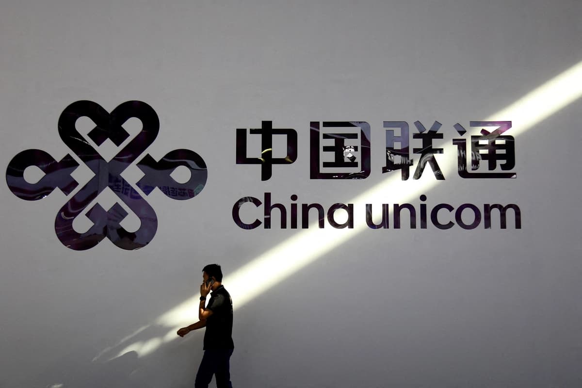 Un hombre con un teléfono móvil pasa junto al logotipo de China Unicom durante el Mobile World Congress en Shanghái el 28 de junio de 2023. (Nicoco Chan/Reuters).
