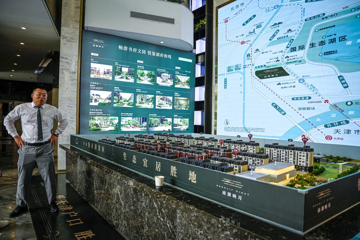 Un vendedor posa junto a la maqueta de un complejo residencial en un centro de venta de propiedades en Tianjin, China, el 5 de junio de 2024. (Jade Gao/AFP vía Getty Images)